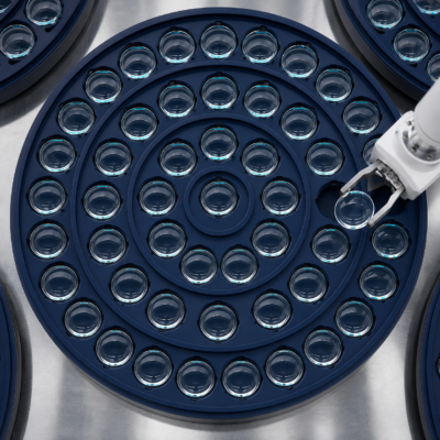 Clear ophthalmic lenses arranged in production trays with robotic handling